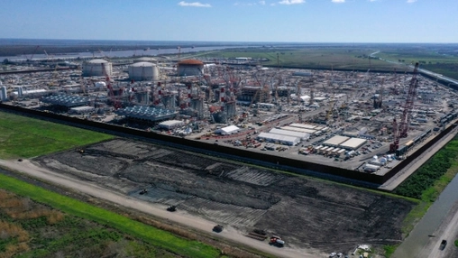 Drone shot of an LNG terminal under construction showing storage domes scaffolding and the access road